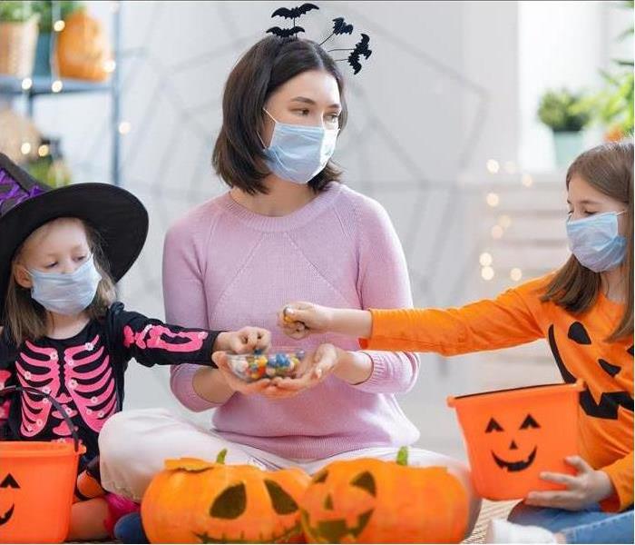 Family with masks carving pumpkins.