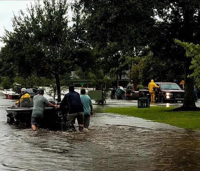 Group of people in a boat on a flooded street.